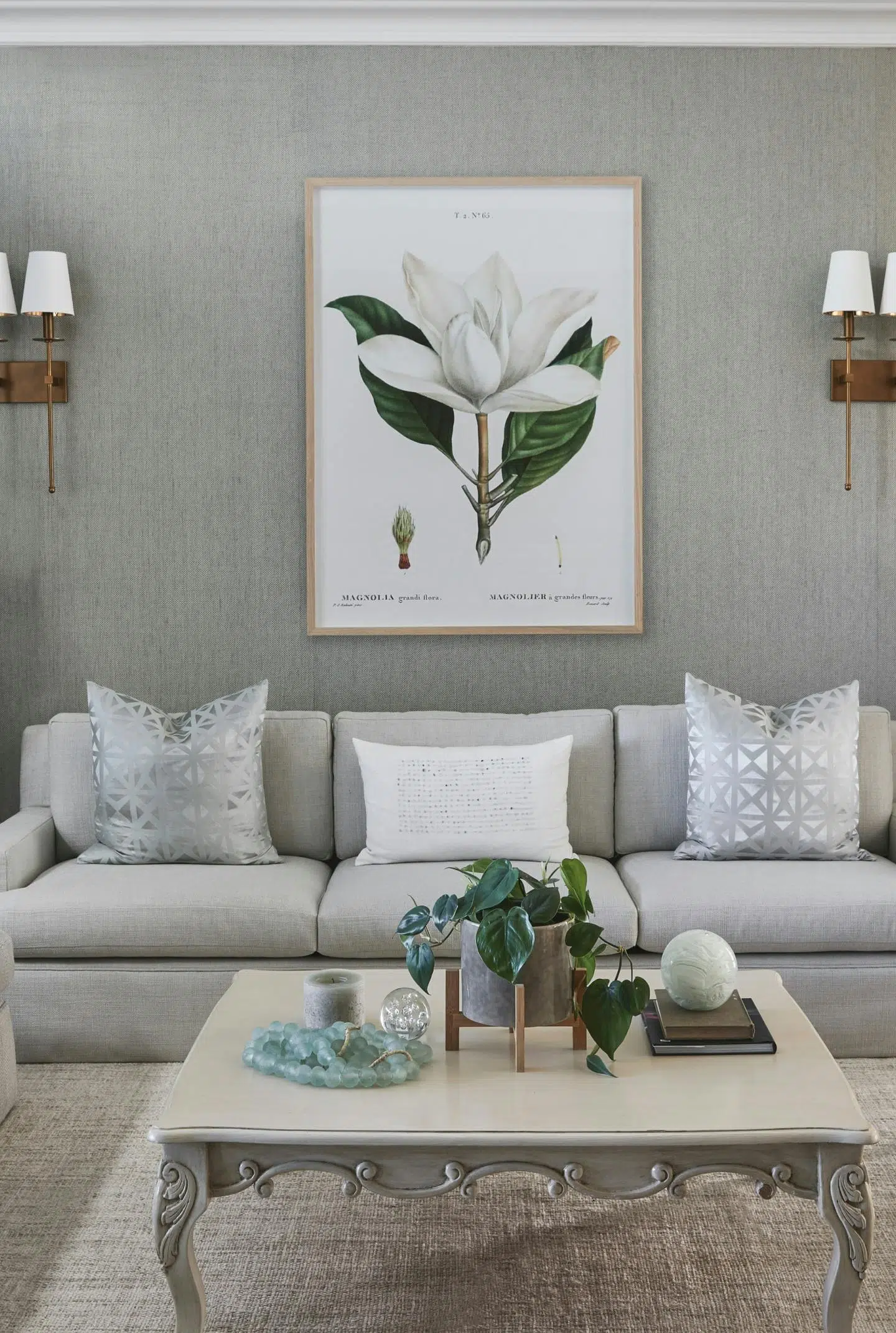 Close-up of a living room with a square coffee table in front of a grey sofa with flower artwork on the wall in the background.